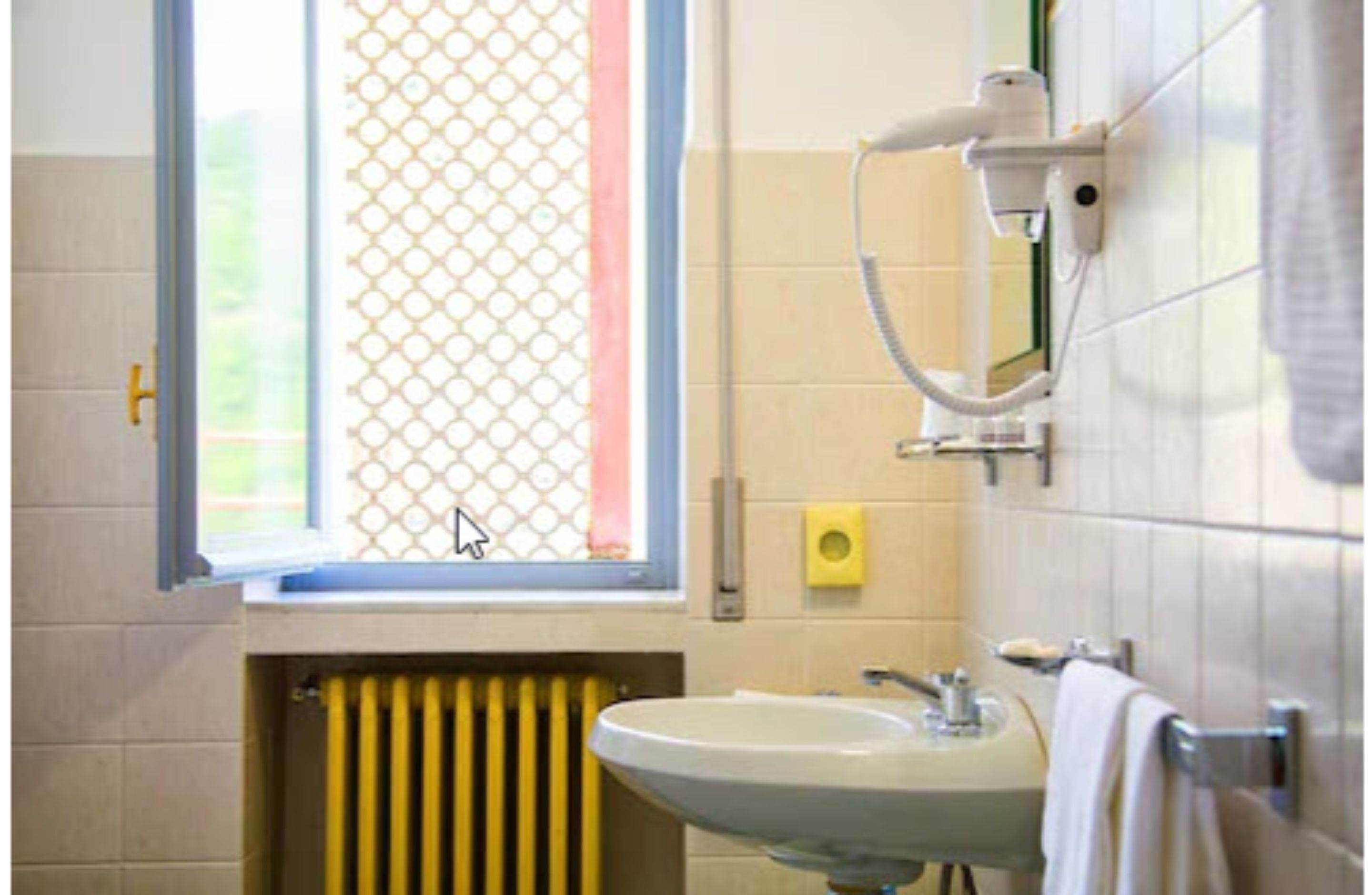 Un baño con ventana, radiador, lavabo y perchero para toallas.