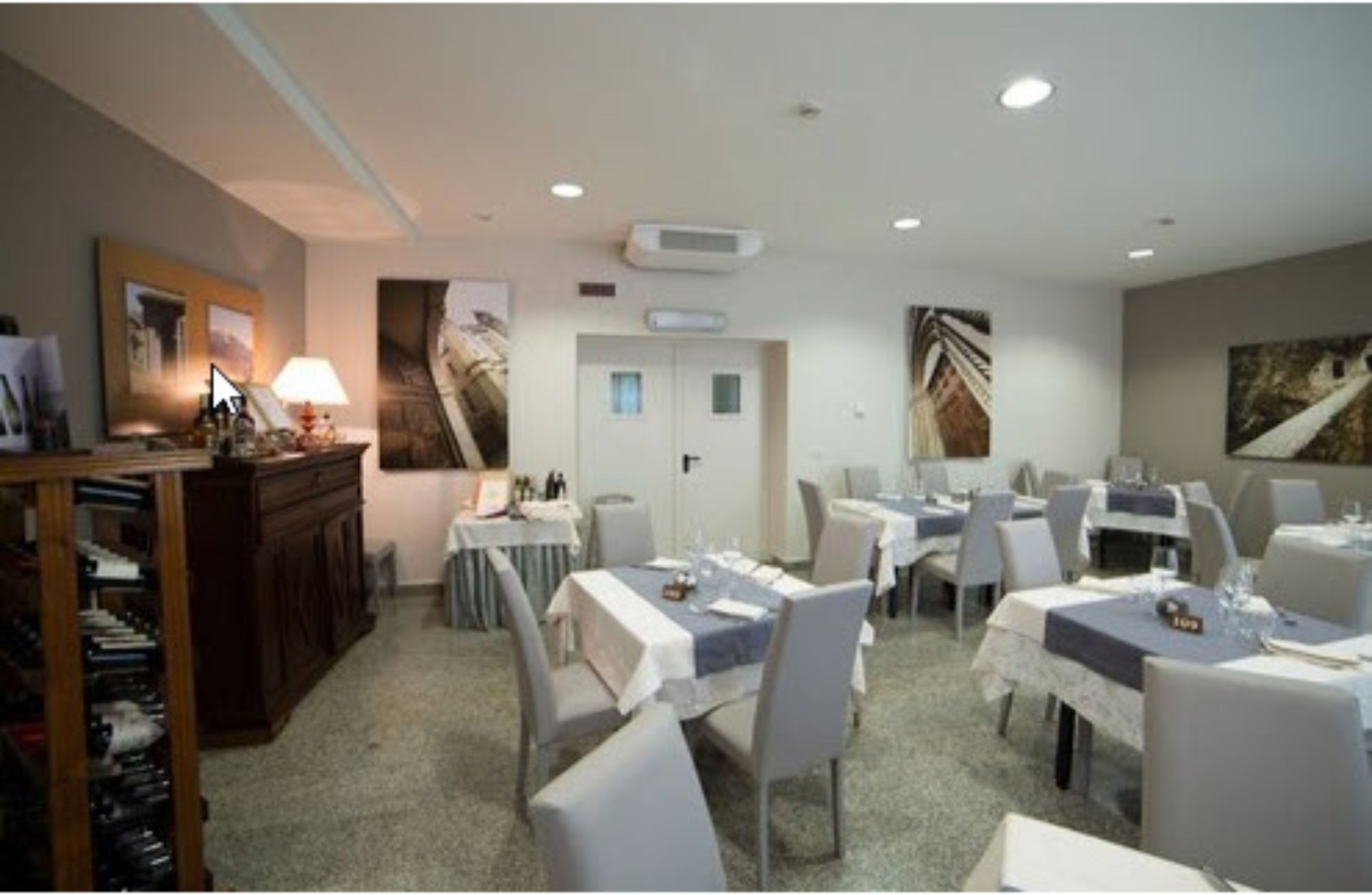 Une salle à manger avec des tables dressées pour les clients, un comptoir d’accueil et un climatiseur fixé au mur.