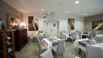 Une salle à manger avec des tables dressées pour les clients, un comptoir d’accueil et un climatiseur fixé au mur.