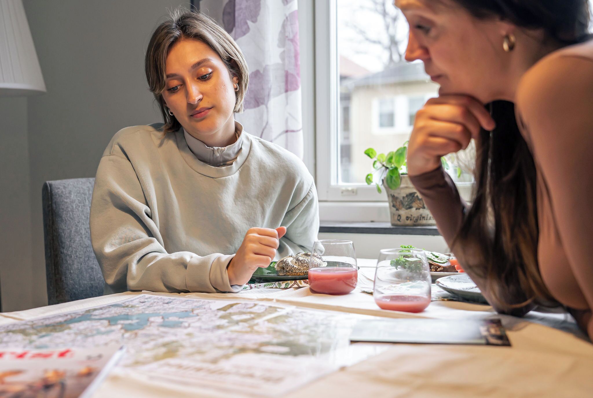 Two people dining at a table with a map and a glass of pink drink.