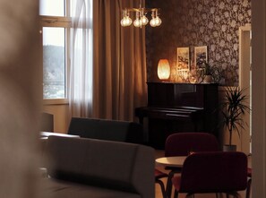 Olohuone, jossa on piano, pöytä ja tuoleja.
