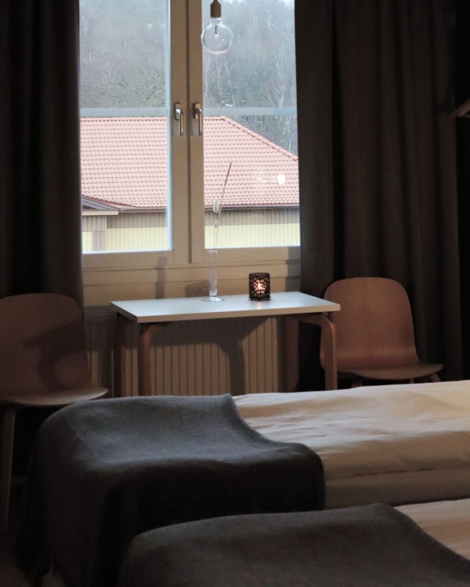 A hotel room with a bed, a small table with a candle, and two chairs.