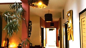 A hallway with a hanging light fixture, a potted plant, and a framed artwork on the wall. - Hotel du Phare (Dakar)