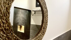A bathroom with a woven mirror, a towel rack, and a tiled wall. - Hotel du Phare (Dakar)