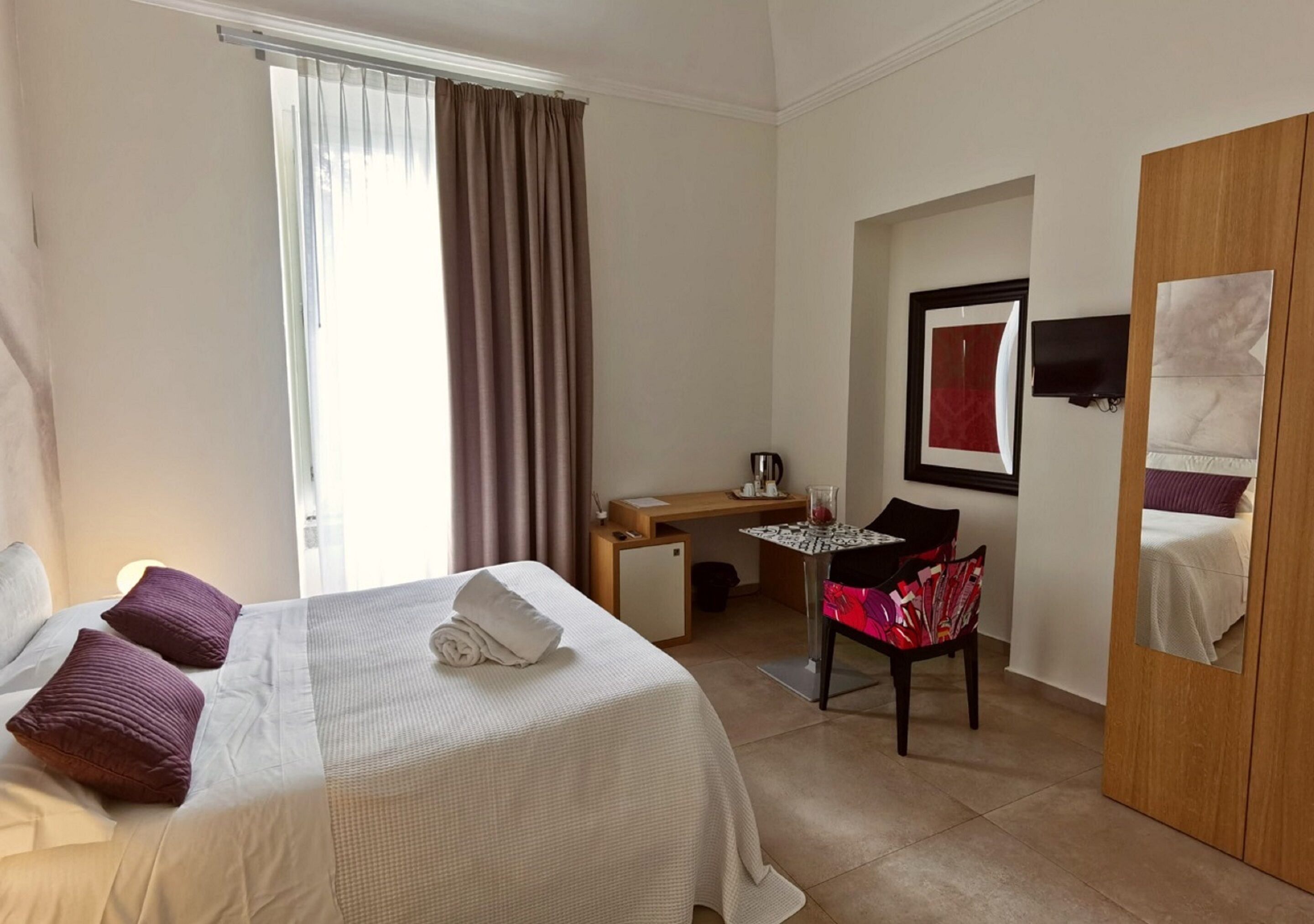 Ein Hotelzimmer mit Bett, Schreibtisch, Stuhl und Kleiderschrank.