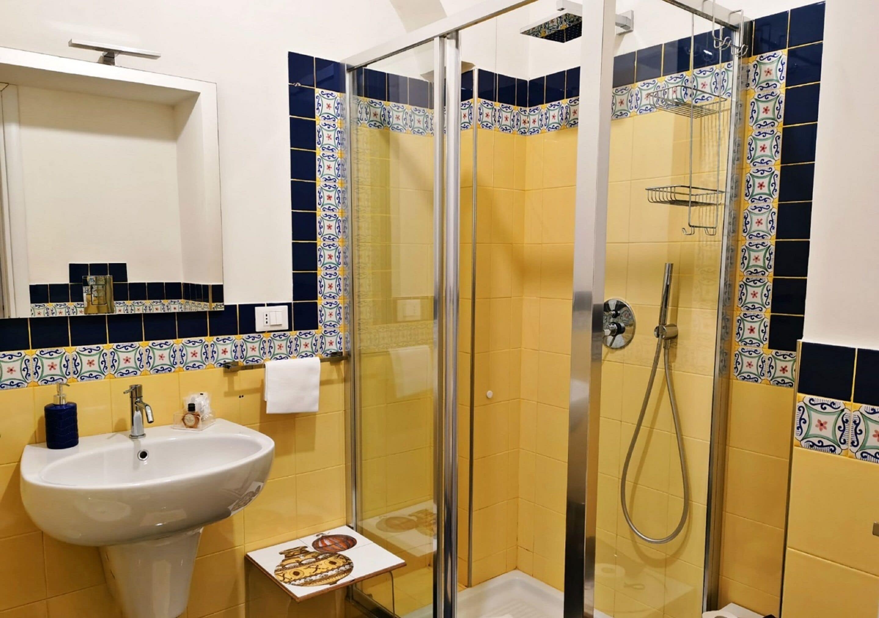 A bathroom with a glass-enclosed shower, a sink, and a mirror.
