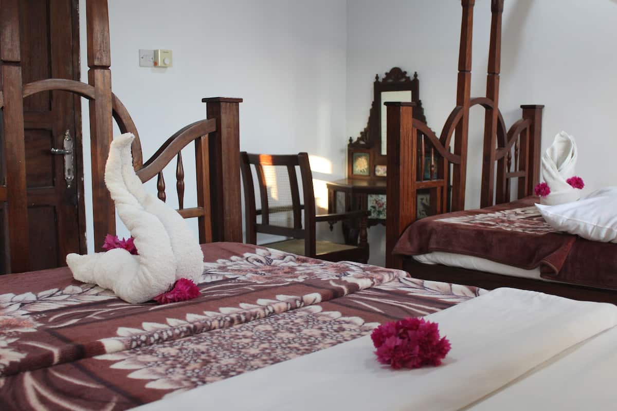 A hotel room with two beds, wooden furniture, and floral decorations.