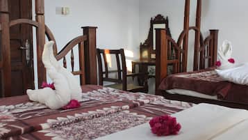 A hotel room with two beds, wooden furniture, and floral decorations.