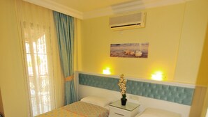 A hotel room with two beds, a nightstand, an air conditioning unit, and a window with curtains. - Ilkiz Beach Hotel (Fethiye)