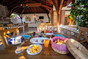 Un espace de restauration en plein air avec des murs en pierre, des meubles en bois et une variété de plats et de boissons disposés sur la table.