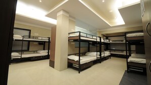 A hotel room with bunk beds, a wooden pillar, and a ceiling with recessed lighting. - Jayaleela dormitory (Mumbai)