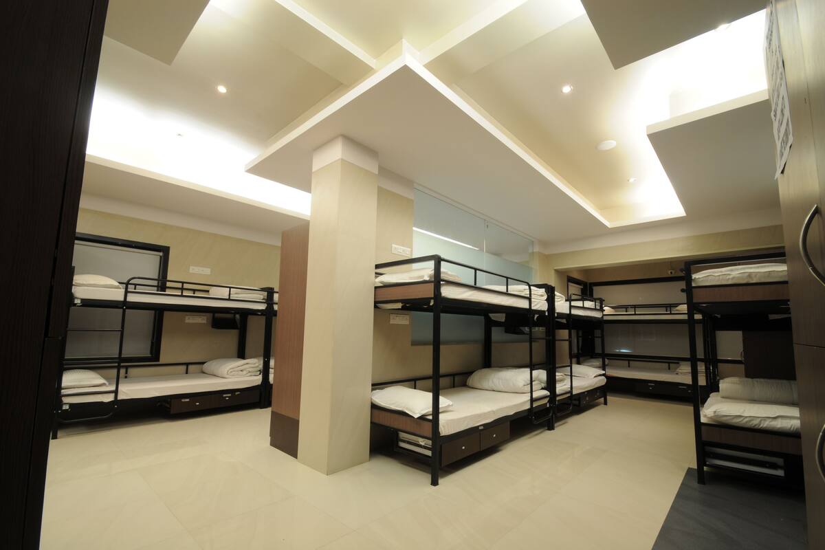 A hotel room with bunk beds, a wooden pillar, and a ceiling with recessed lighting.