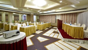 A conference room with multiple tables, chairs, and a podium. - Jayaleela dormitory (Mumbai)