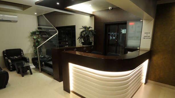 A reception desk with a modern design, a staircase, and seating area with chairs and a small table. - Jayaleela dormitory (Mumbai)