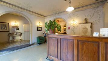 Classic reception area with a reception desk, framed pictures, and a comfortable chair.