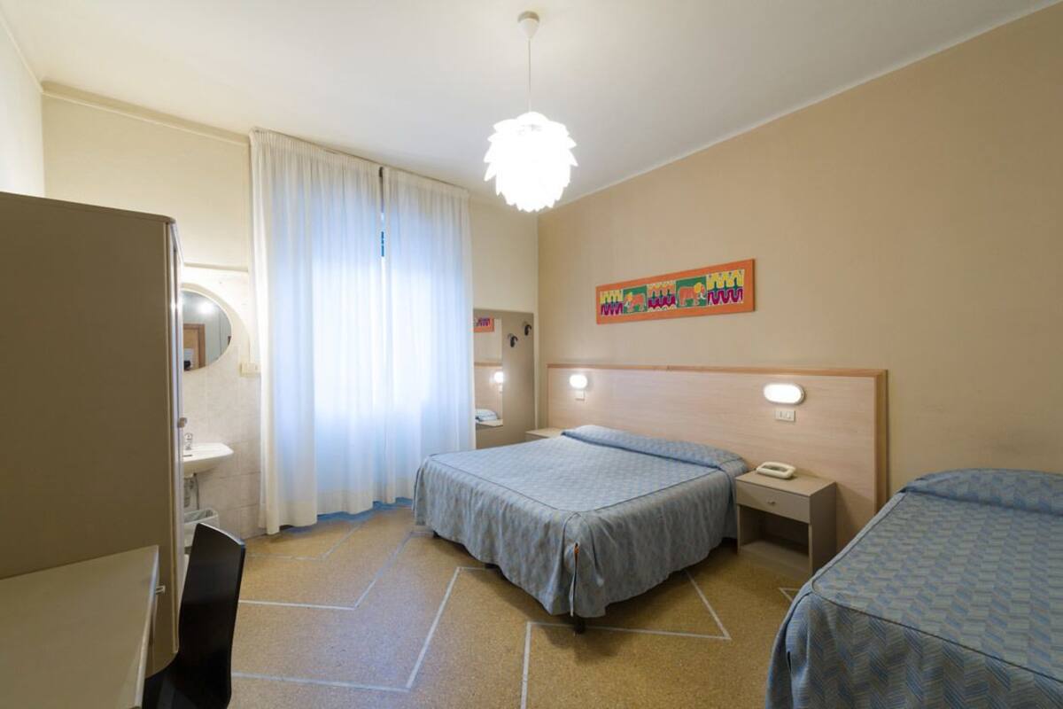 Habitación de hotel con dos camas, baño, escritorio e iluminación en el techo.