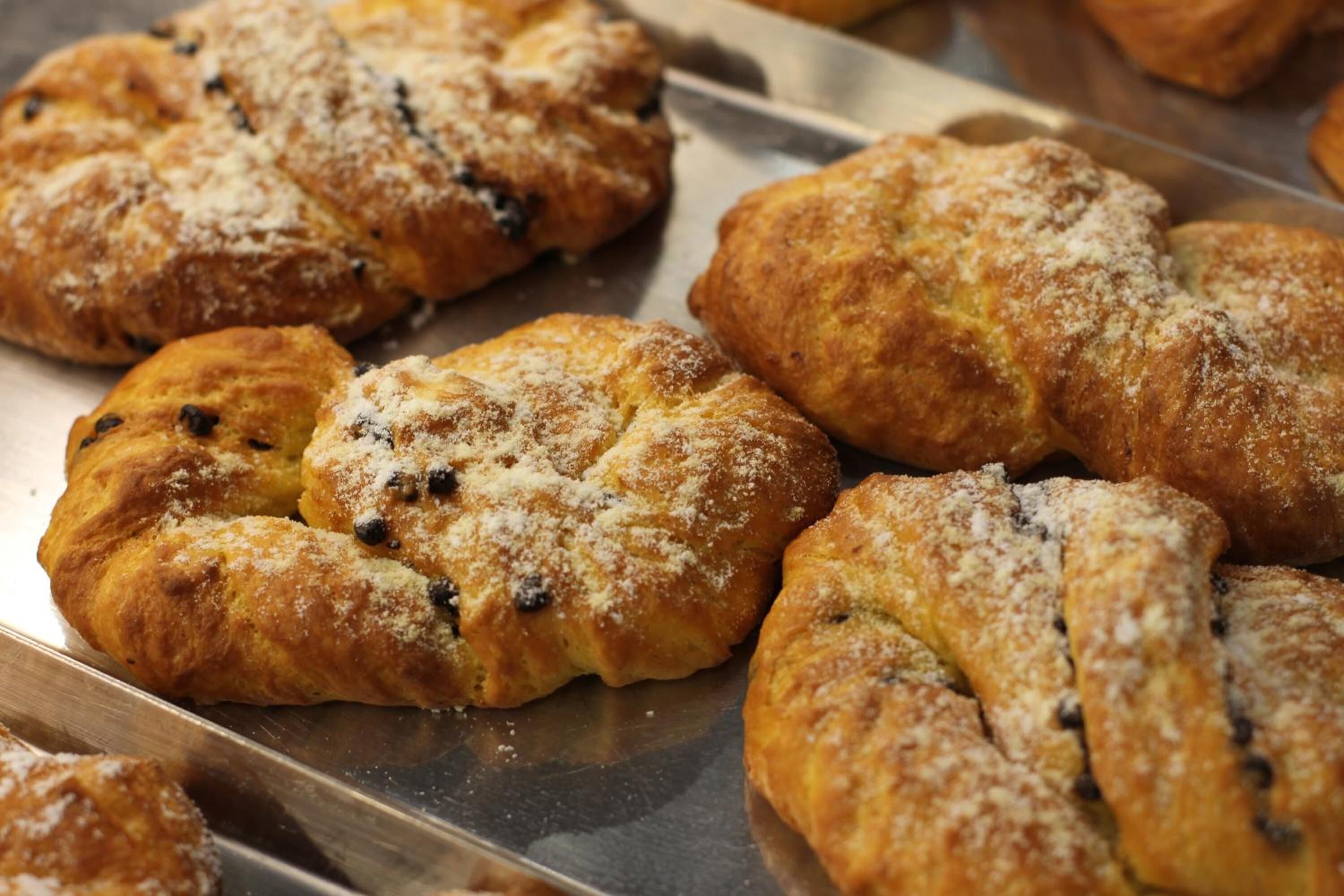 Een dienblad met versgebakken gebak, waarschijnlijk croissants, bestoven met poedersuiker.