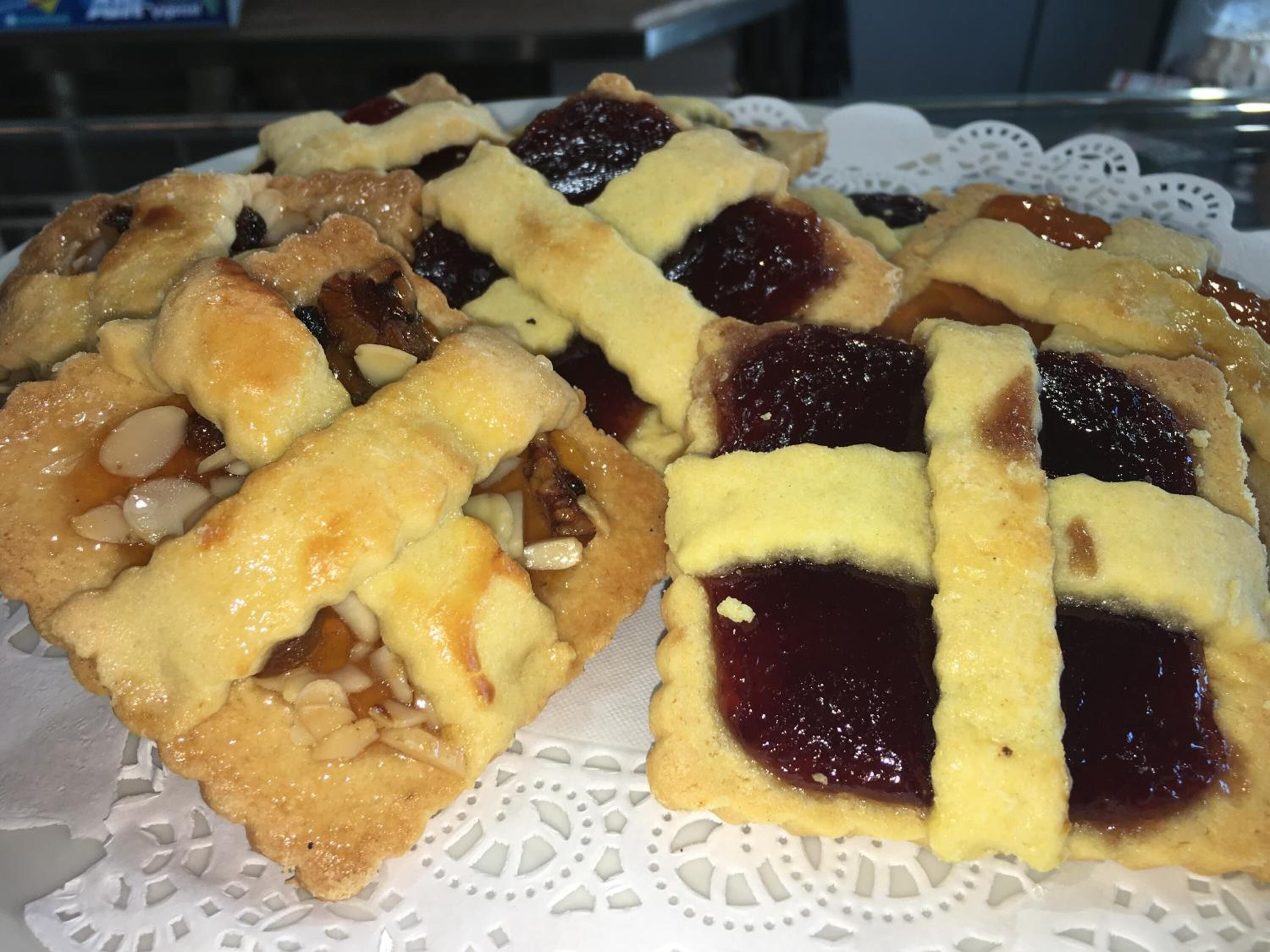A plate of fruit tarts with a lattice crust on a white doily.