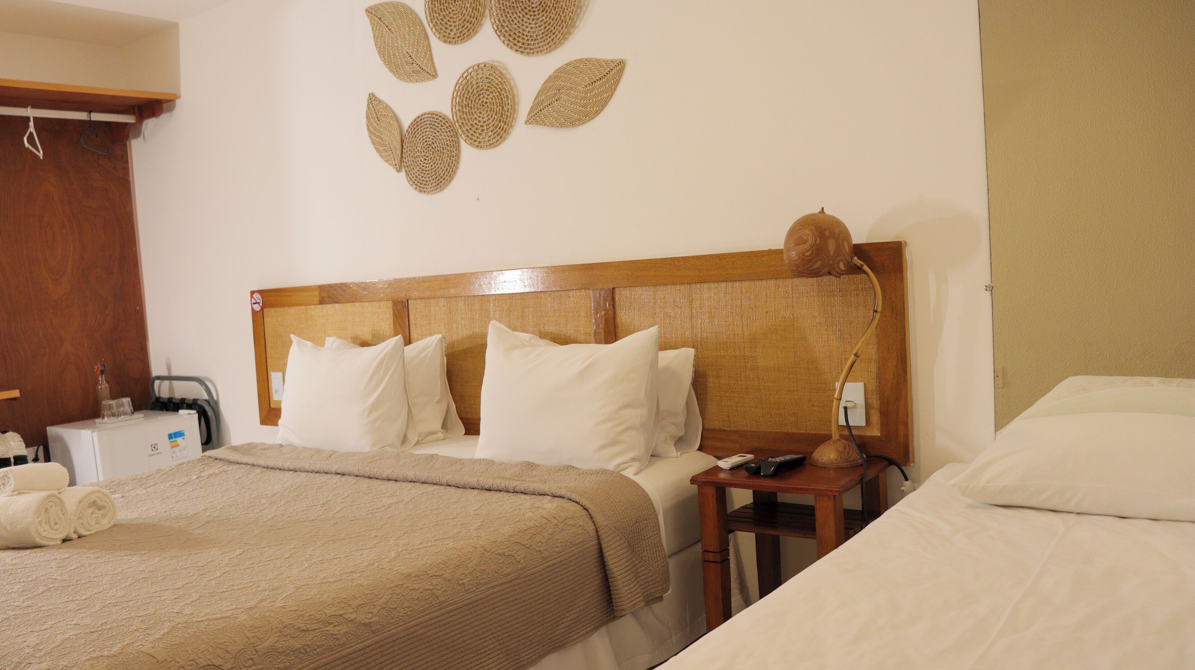 A hotel room with a large bed, a bedside table with a lamp, and a wall decoration above the bed.