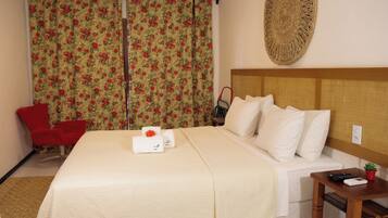 Ein Hotelzimmer mit einem Bett, einem roten Sessel, einem kleinen Tisch mit Fernbedienung und einem Wanddekor.