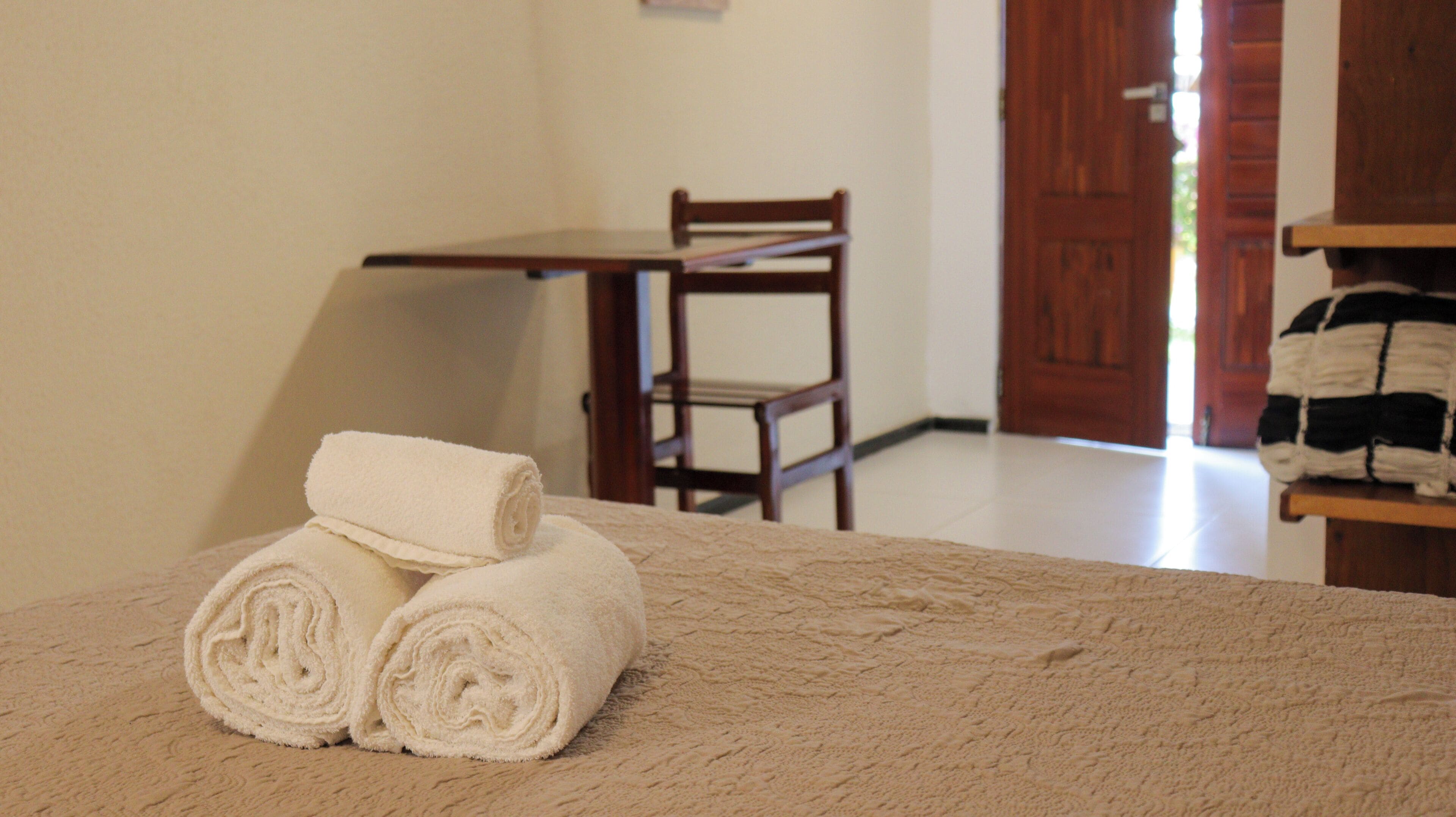 A room with a bed, a wooden chair, and a table.