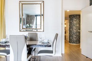 A modern dining area with a marble countertop, white chairs, and a large mirror above the table. - Point West (London)