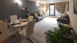 Una sala de estar moderna con comedor, un conjunto de sofás y un ventanal con cortinas.