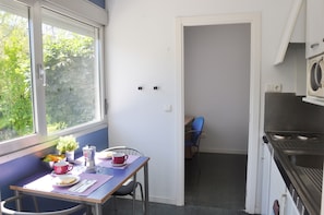 Ett kompakt kök med matplats, tvättmaskin och utsikt över grönområden utanför.