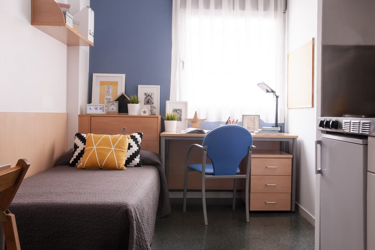 Une chambre à coucher de taille réduite, comprenant un lit, un bureau et une chaise.