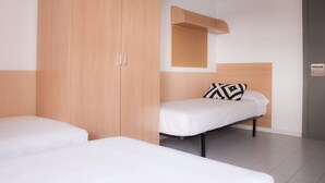 A bedroom with two single beds, a wooden wardrobe, a small wooden shelf, and a wall-mounted bulletin board. - Residencia Universitaria Resa Tomás Alfaro Fournier - Centro Adscrito a REAJ - Campus Accomodation (Vitoria-Gasteiz)