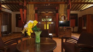 Una habitación tradicional con techo de madera, una mesa de comedor con sillas, un televisor y una puerta de madera decorativa.
