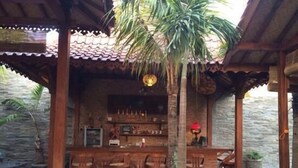 Una zona con barra de madera, techo de baldosas y paredes de piedra.
