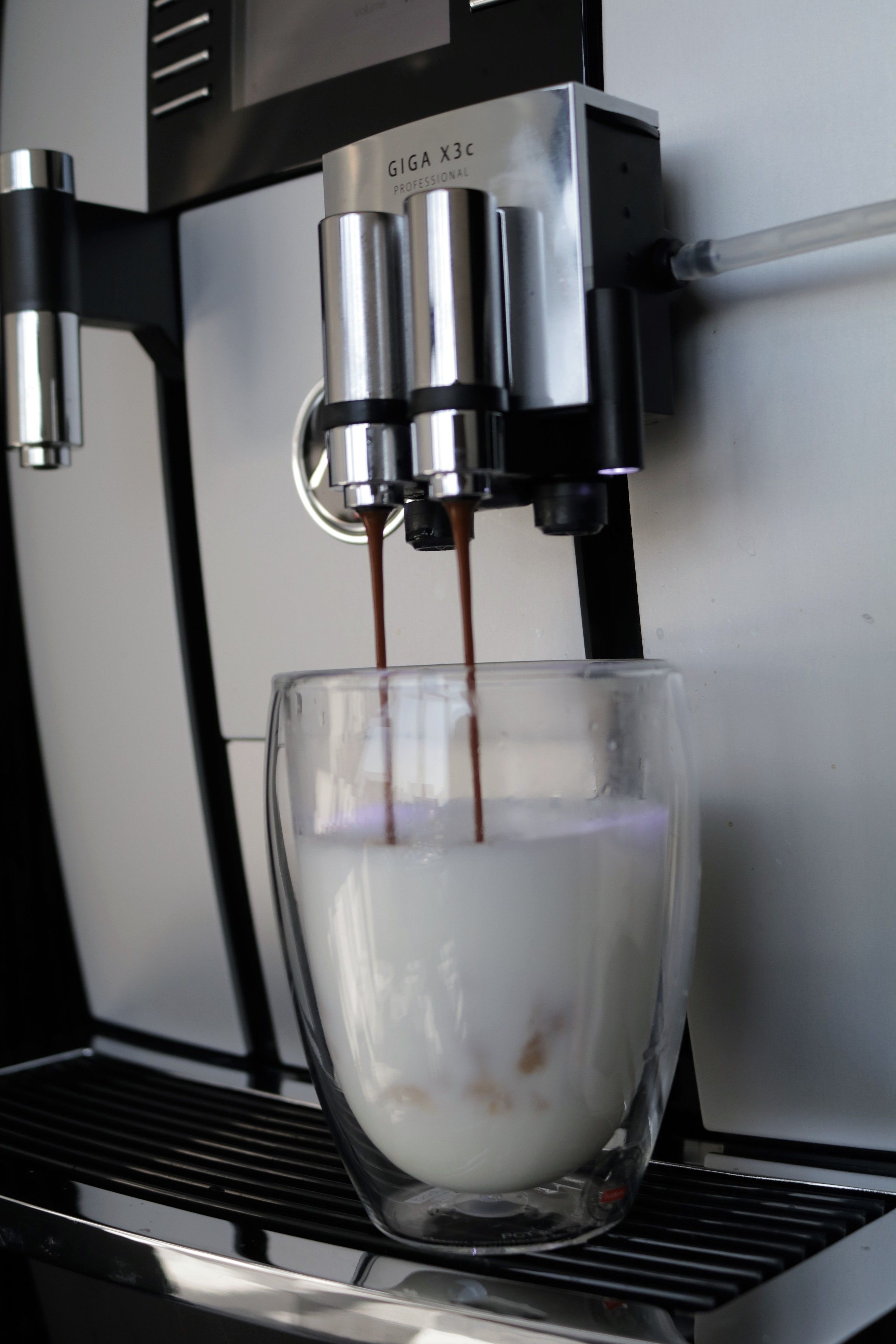 Una máquina de espresso profesional sirviendo café en una taza de vidrio.