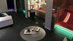 A modern hotel room with a heated stone bath, a dining table with a meal, and a sofa. - B&B For 2 - Wellness For 2 (Bruges)