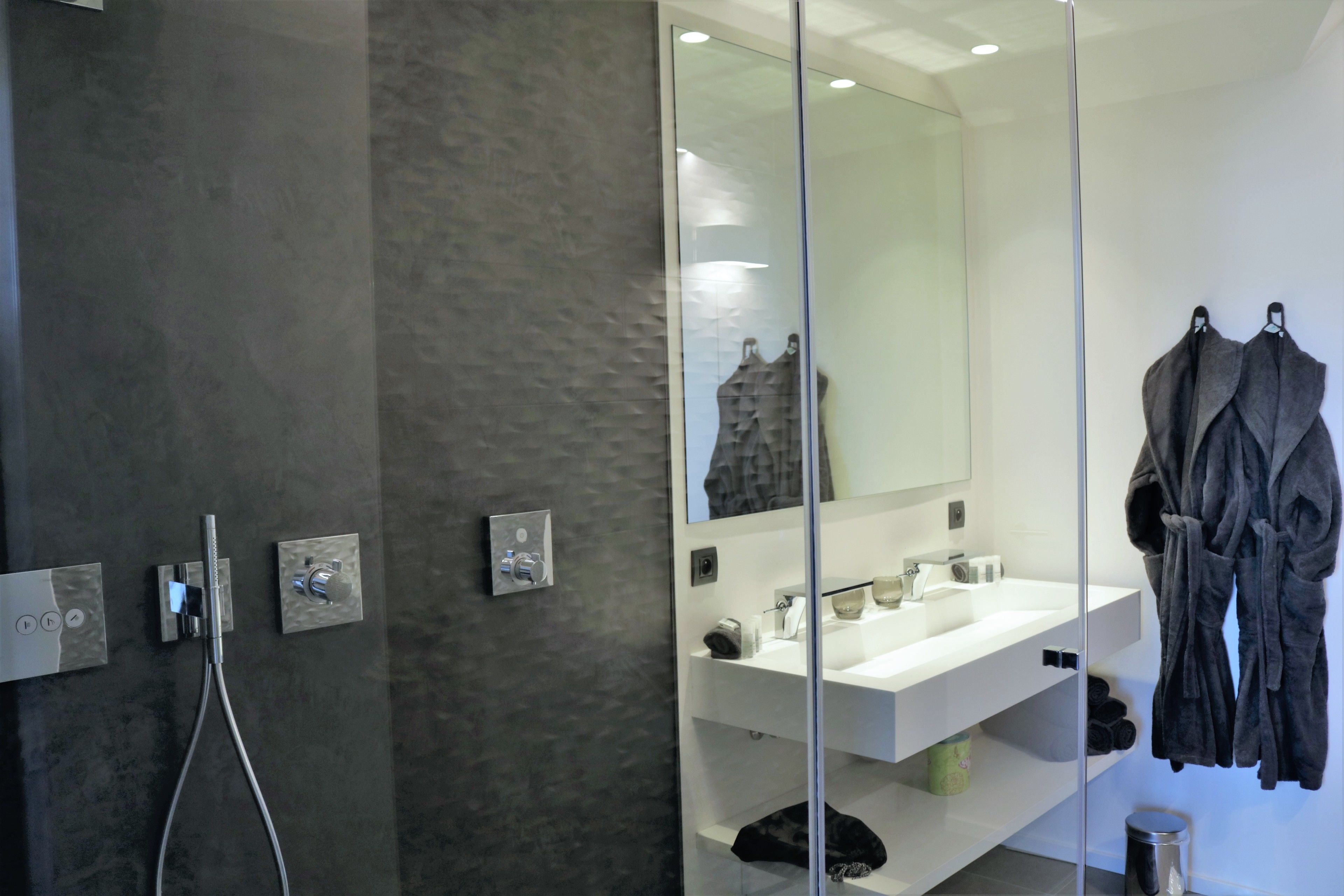 A modern bathroom with a glass shower enclosure, a large mirror, and a white sink with a vanity.