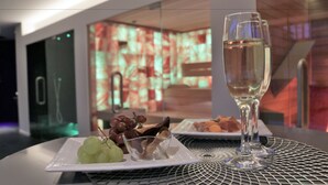 A table with a glass of champagne, a plate with grapes, and a bowl of nuts. - B&B For 2 - Wellness For 2 (Bruges)