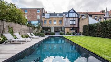 Una piscina al aire libre, sillones reclinables de piscina