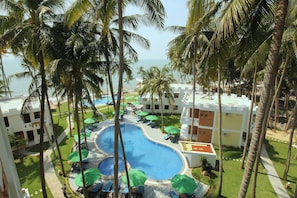 Un resort con una piscina centrale circondata da palme e lettini.