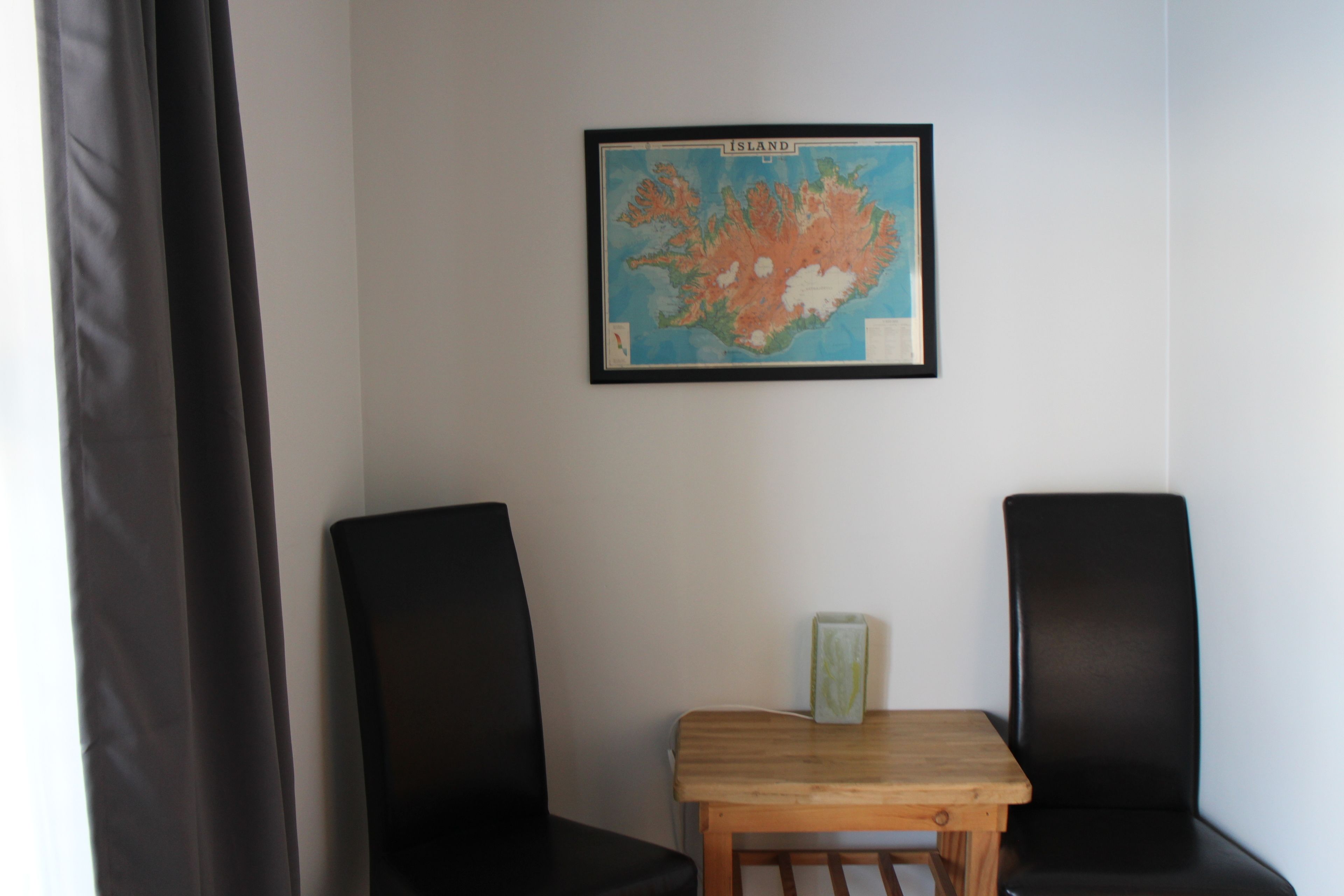 A room with two black chairs, a wooden table, and a framed map on the wall.