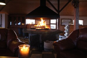A cozy room with a fireplace, leather chairs, and a table with a candle. - Hótel Á (Borgarbyggd)