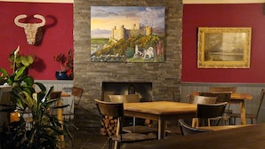 A dining area with a stone fireplace, wooden tables, and chairs. - Y Branwen Restaurant & Rooms - Adult Only and Dog Friendly (Harlech)