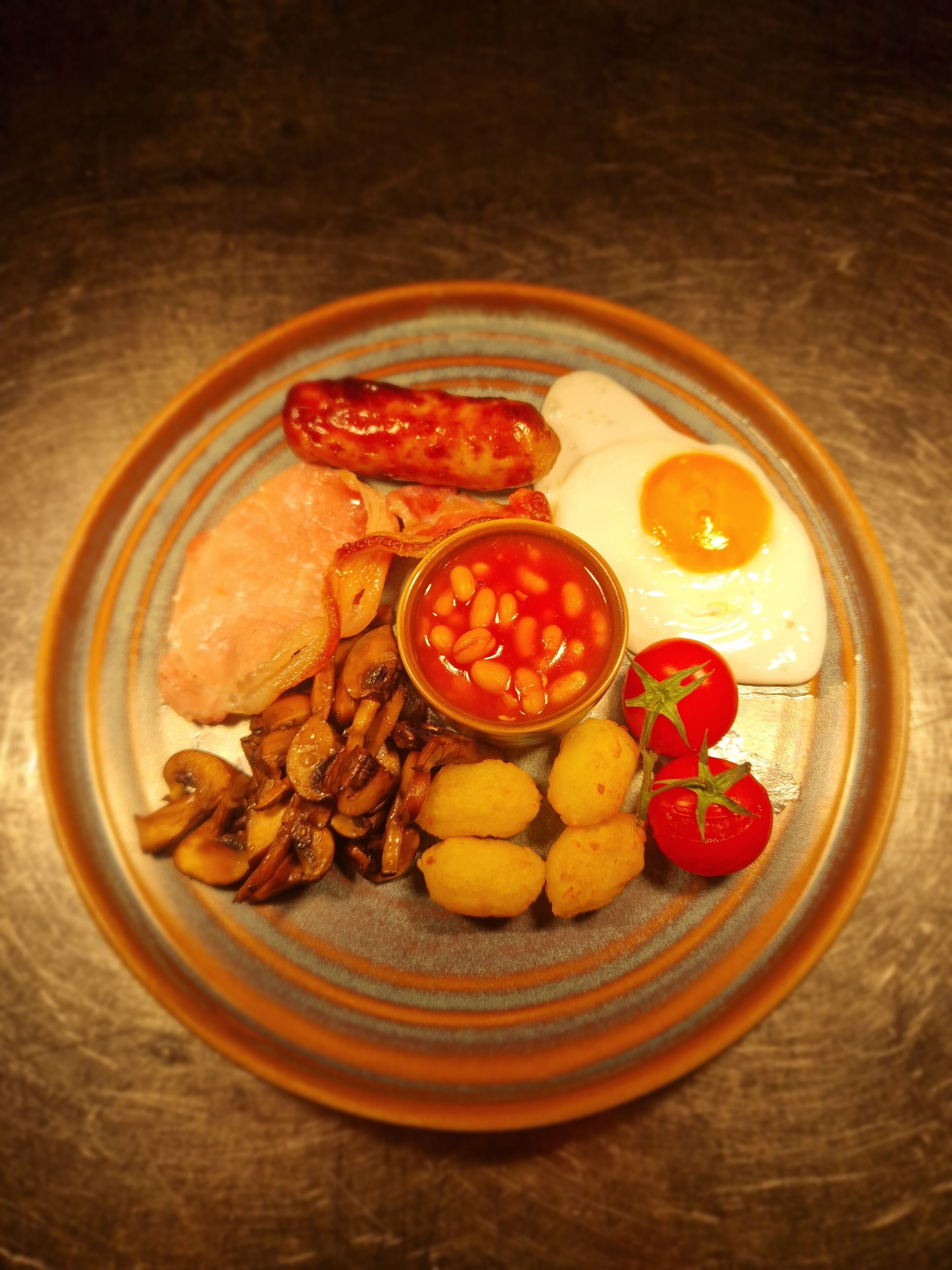 Un plato de comida con huevos, salchichas, champiñones, frijoles y tomates.