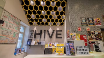 A bar area with a hexagonal light fixture, a sign for 'The Hive', and various promotional materials.