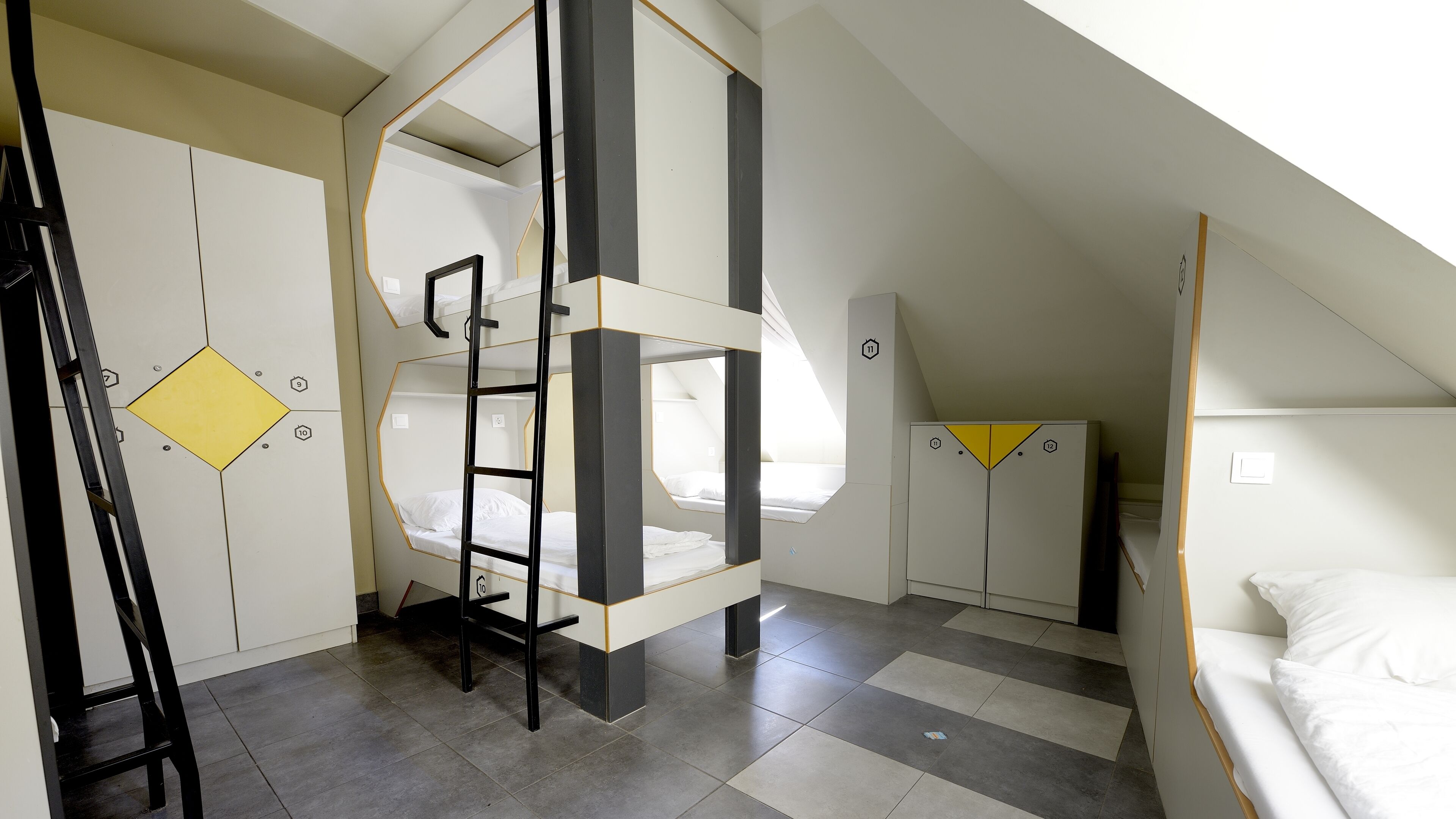 Ein Schlafsaalzimmer mit Etagenbetten, einer Stehleiter und einem Schachbrettboden.