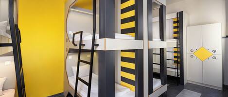 A room with bunk beds, a white wardrobe, and a yellow accent wall.