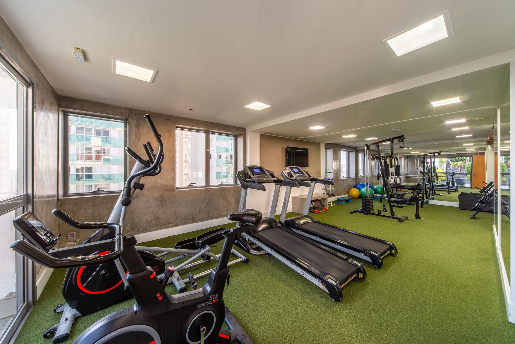 Academia com esteiras, bicicletas ergométricas e bolas de exercício.