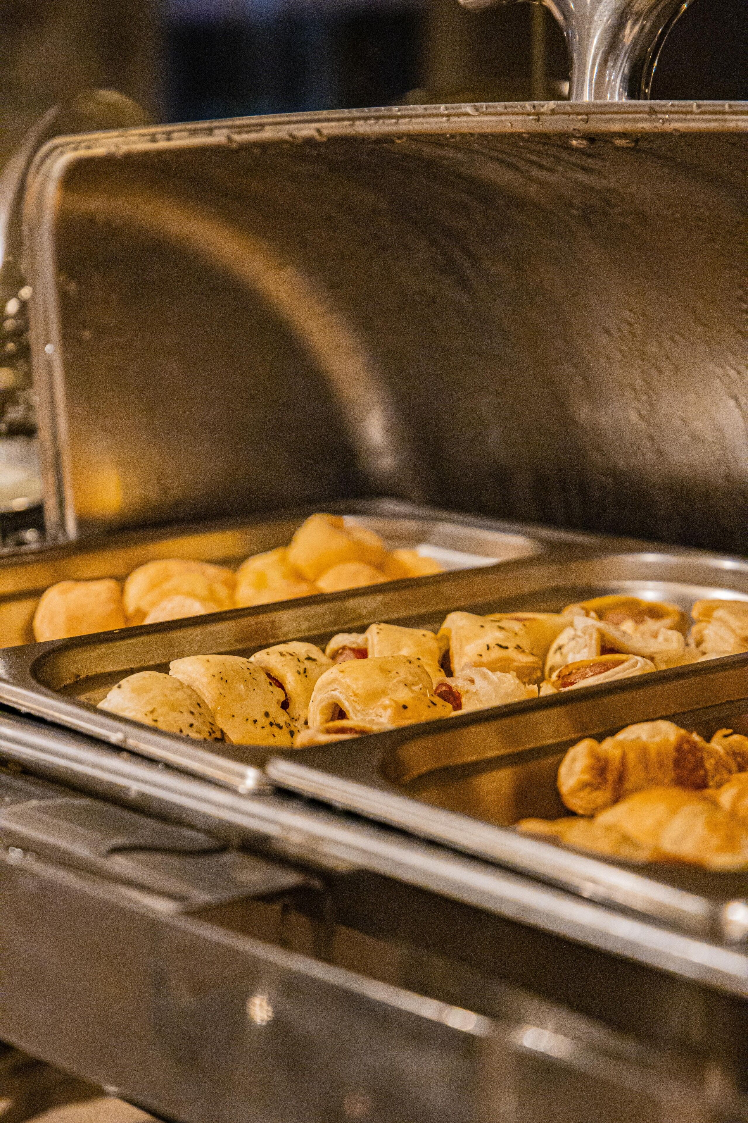 A buffet with various baked goods, including pastries and bread rolls.