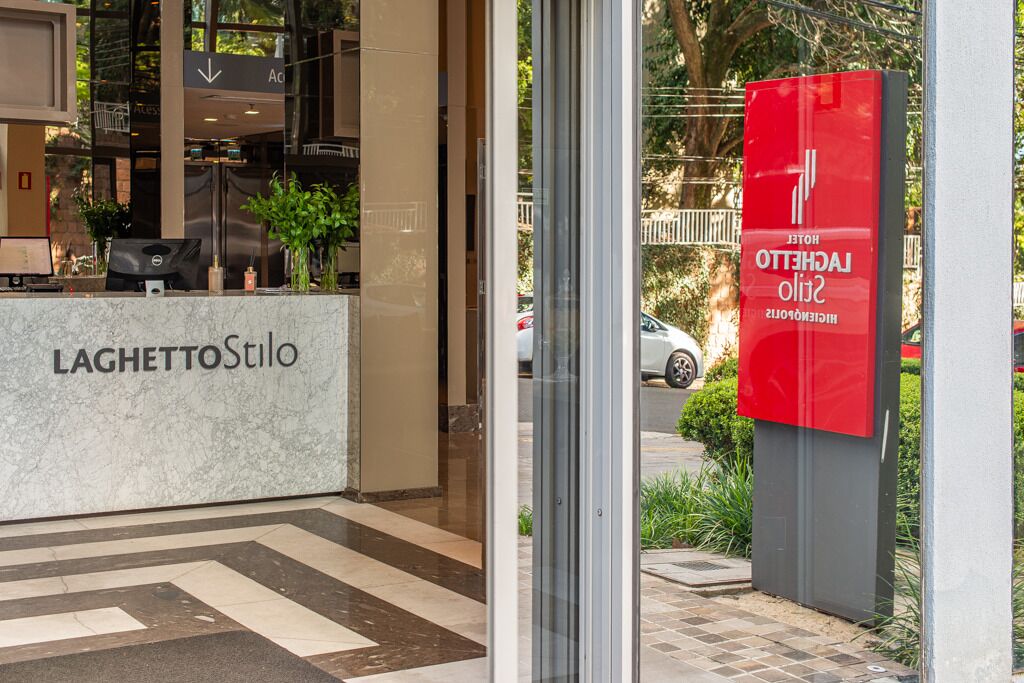 A hotel reception area with a marble counter, a red sign, and a view of the street outside.