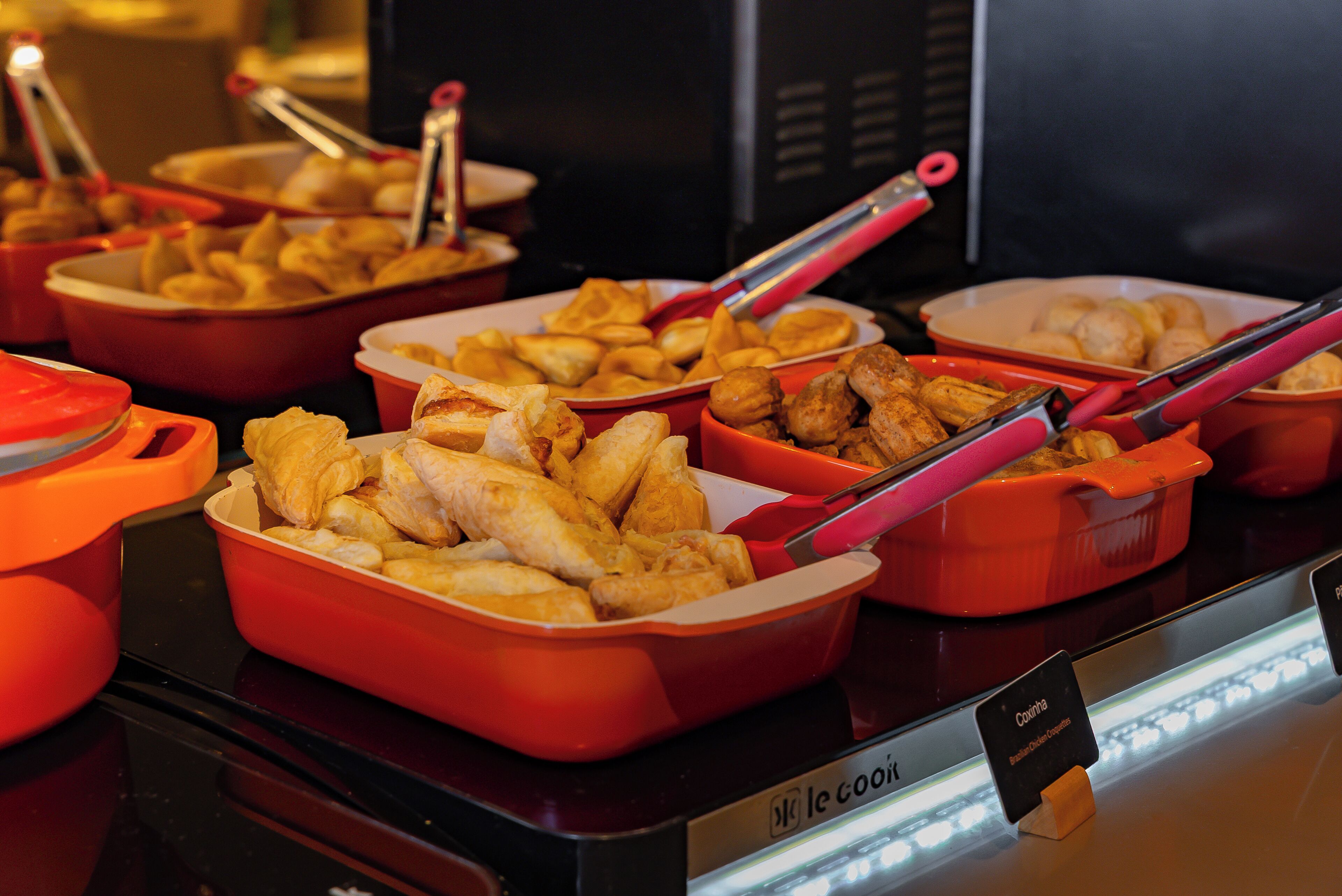 A buffet with various dishes in orange serving containers.