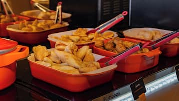 A buffet with various dishes in orange serving containers.